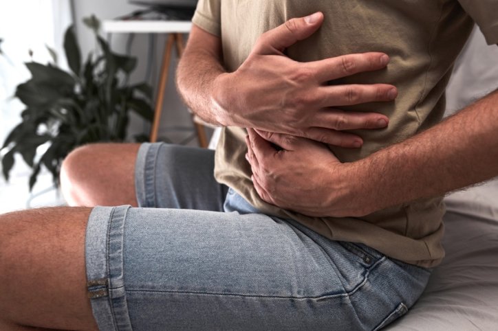 Ein Mann mit Verdacht auf Bauchaortenaneurysma hält sich den Bauch.