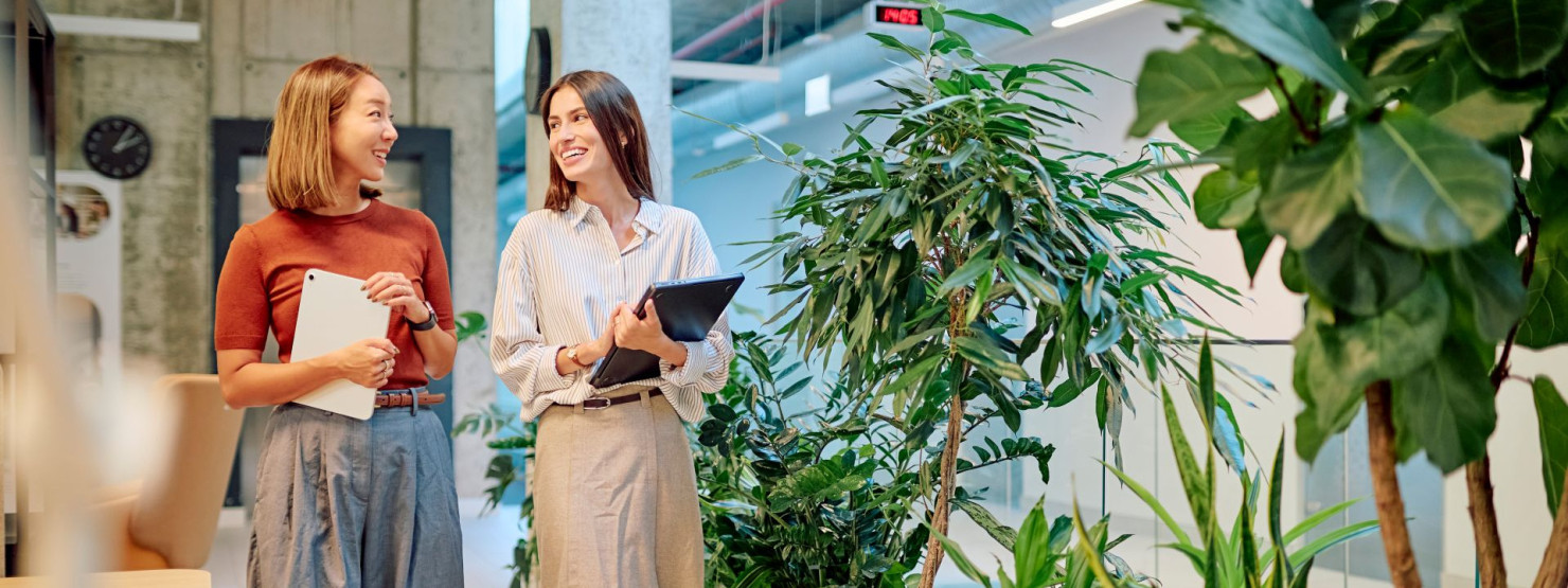 Zwei Beschäftigte laufen gemeinsam durch die Räumlichkeiten eines Unternehmens und unterhalten sich.