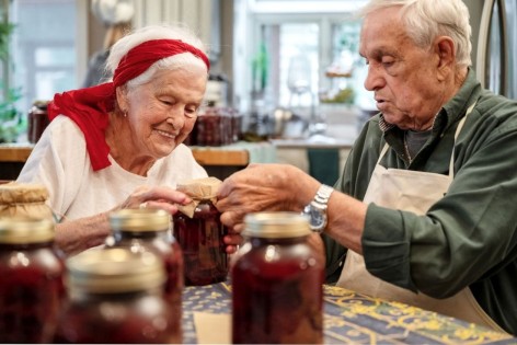 Ein Senioren-Paar sitzt in ihrer Küche und hat frisches Obst fermentiert. 
