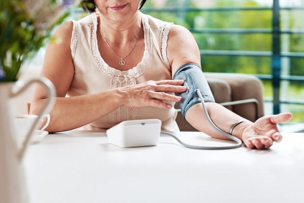 Eine ältere Frau kontrolliert mit einer Selbstmessung ihren Blutdruck
