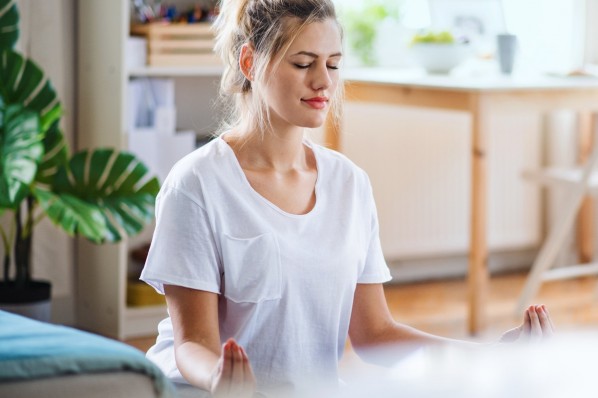 Junge Frau macht entspannungsübungen in ihrem Wohnzimmer