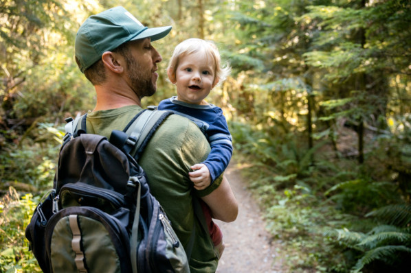 Vater trägt sein Kleinkind im Wald auf dem Arm