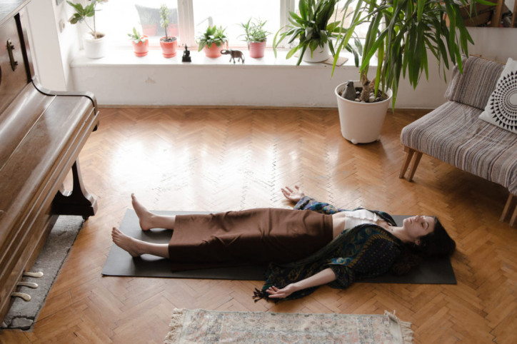 Eine Frau praktiziert Yoga Nidra auf einer Matte