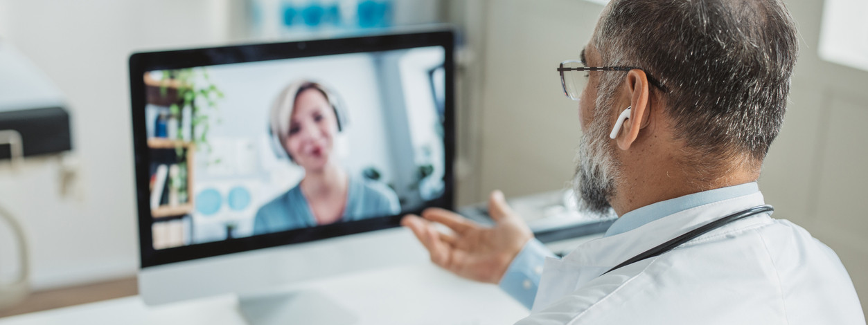 Ein Arzt spricht mit einer Ärztin per Videotelefonie über seinen Computerbildschirm.