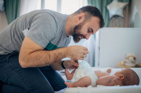 Ein Vater wickelt sein neugeborenes Baby