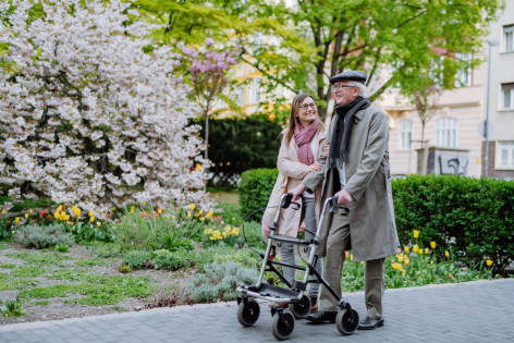 Ein an Osteoporose erkrankter Senior geht mit seiner Tochter spazieren