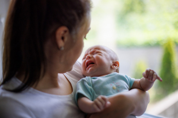 Eine Mutter trägt ein Baby mit Regulationsstörung auf dem Arm
