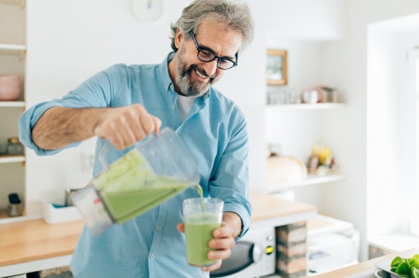 ein mann mitte 50 mixt sich einen grünen Smoothie