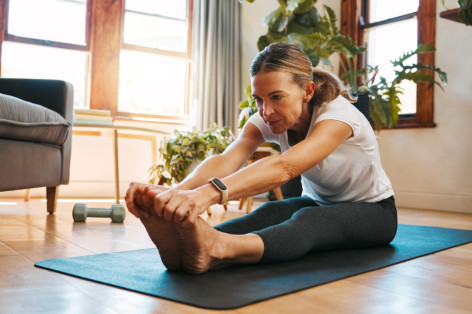 Eine Frau führt zuhause auf der Matte Mobility Training durch.