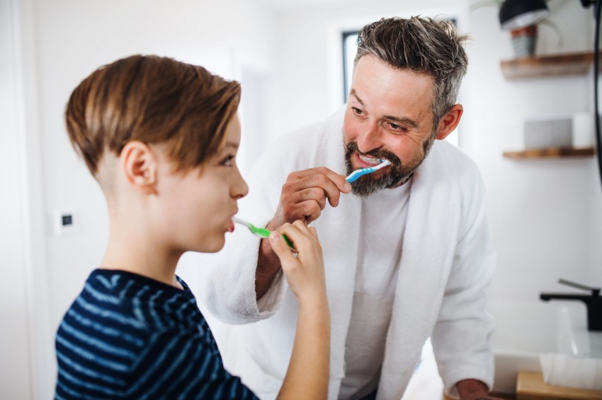 Ein Vater putzt mit seinem etwa 10 jährigen Sohn gemeinsam die Zähne.