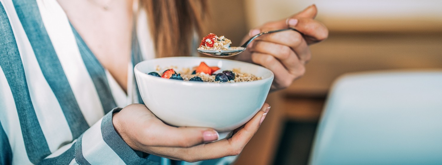 Junge Frau isst Porridge mit Beeren