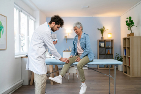 Ein Orthopäde in Dessau untersucht das Knie einer Patientin.