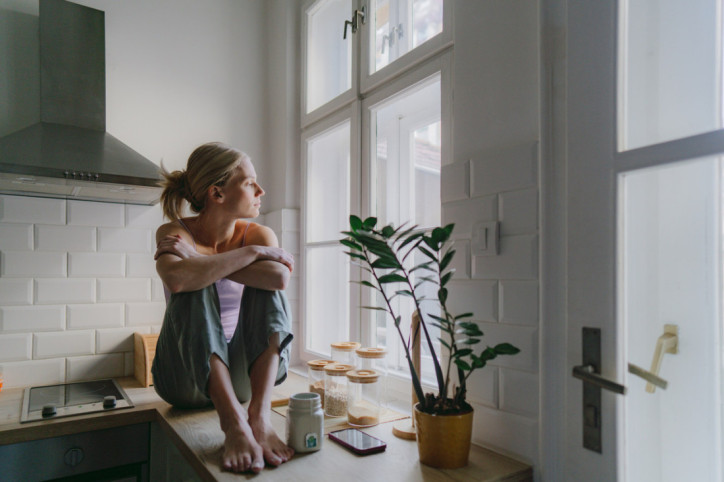 Frau mit Sommerdepression schaut aus Fenster
