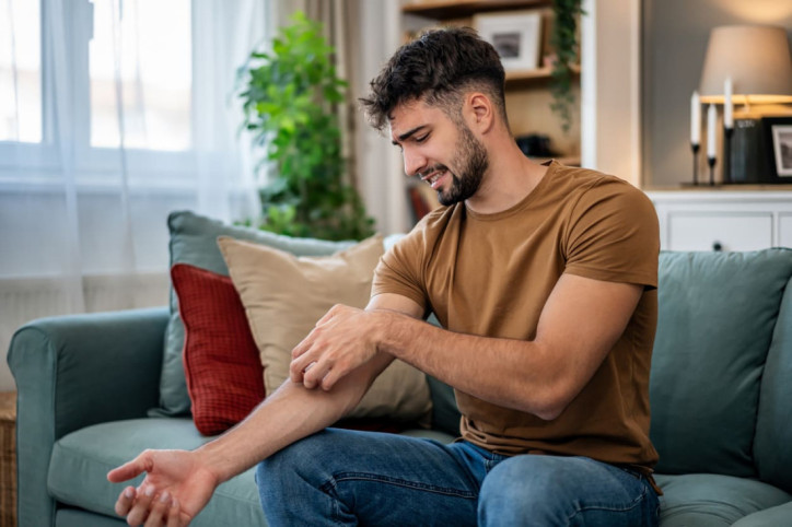 Junger Mann mit juckender Badedermatitis