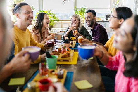 Eine Gruppe gut gelaunter Menschen frühstückt gemeinsam