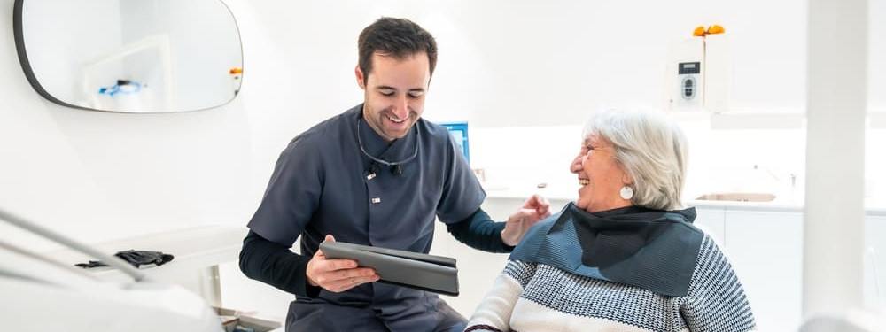 Junger Zahnarzt behandelt Seniorin in seniorenfreundlicher Praxis