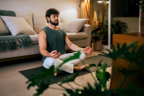 mann mit Bart meditiert in seinem Wohnzimmer