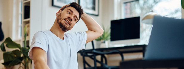 Ein etwas 35-jähriger Mann macht Nackenübungen auf seiner Matte zuhause.