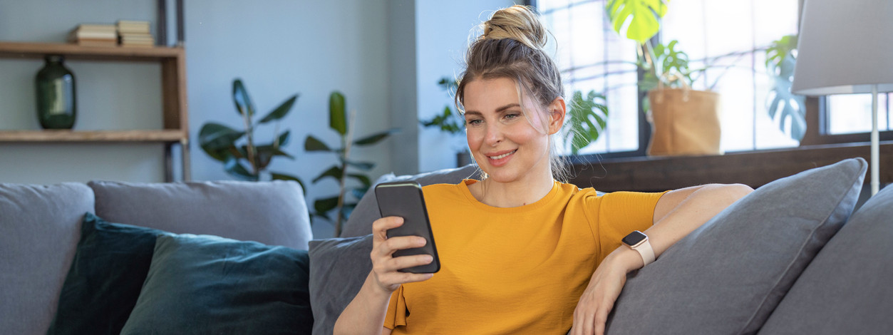 Frau mit Smartphone auf dem Sofa