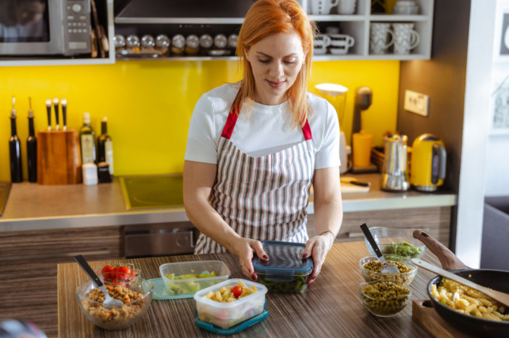 Eine Frau bereitet für ihre Ernährungsumstellung ihr Essen als Meal Prep vor.