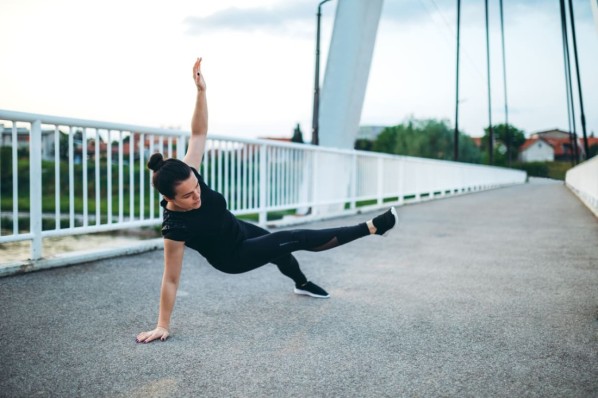 Eine Frau beim Warm-Up für eine Parkour-Session
