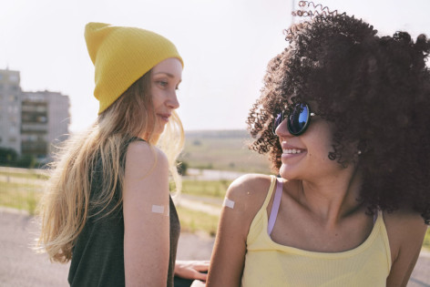 Zwei Mädchen zeigen ihre geimpften Arme mit einem Pflaster darauf. Sie haben die HPV-Impfung erhalten.