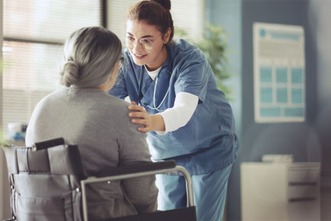 Junge Krankenschwester betreut Seniorin im Rollstuhl