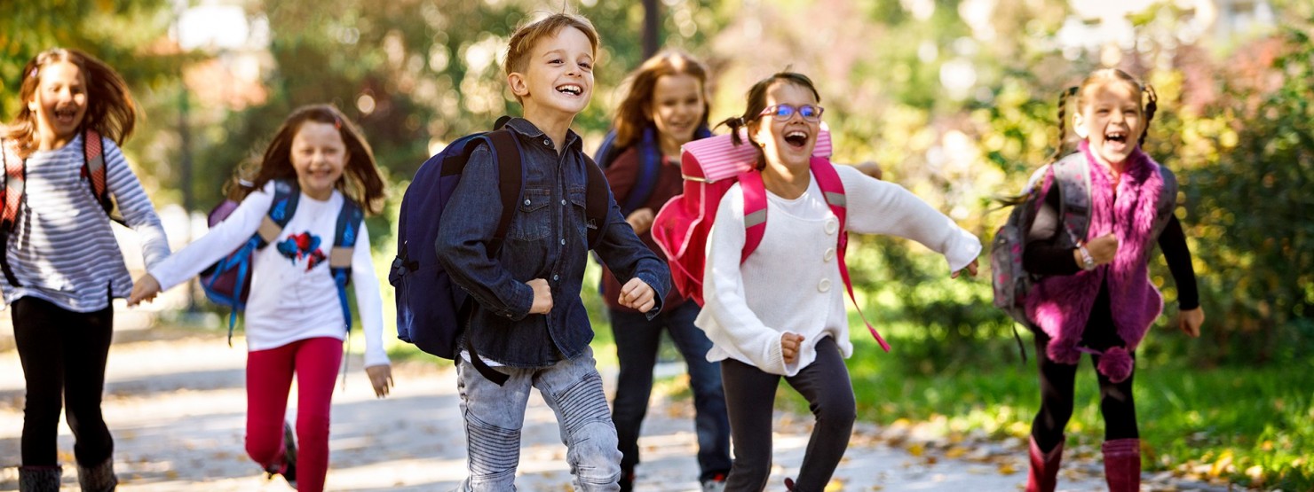 Erstklässler mit Schulranzen auf dem Weg zur Schule.