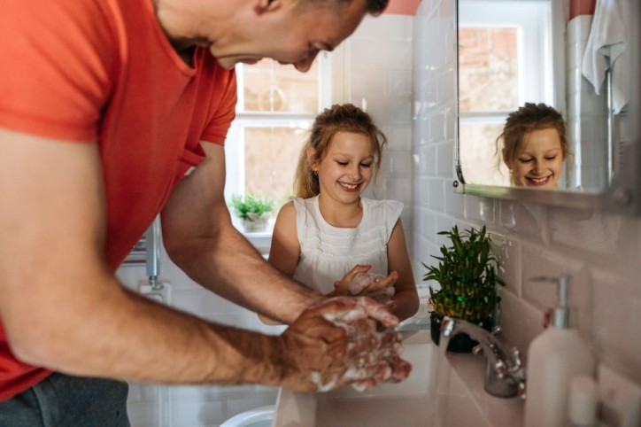 Ein Vater und seine Tochter waschen gemeinsam Hände zum Schutz vor Ringelröteln
