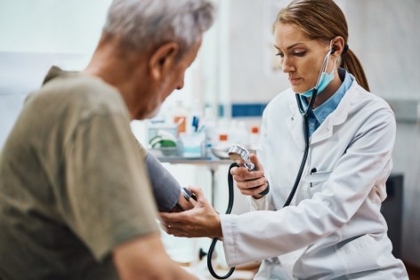 Eine Ärztin misst bei einem Patientin den Blutdruck.