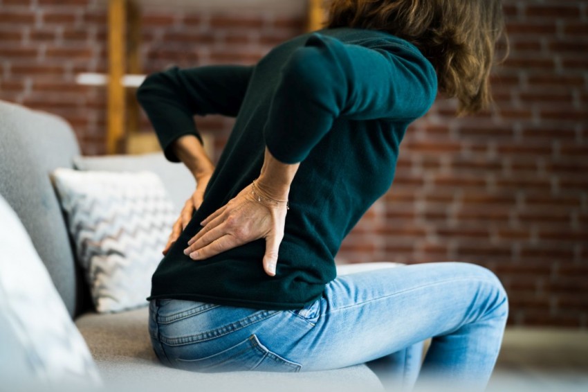 Eine Frau mittleren Alters hält besorgt ihren schmerzenden Rücken.