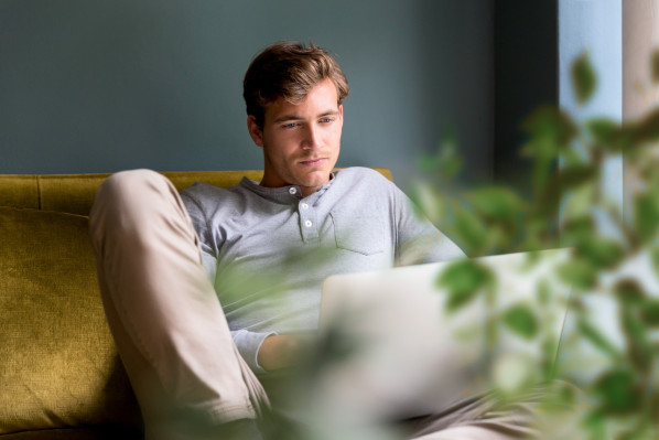 junger mann recherchiert mit nachdenklichem Blick am laptop