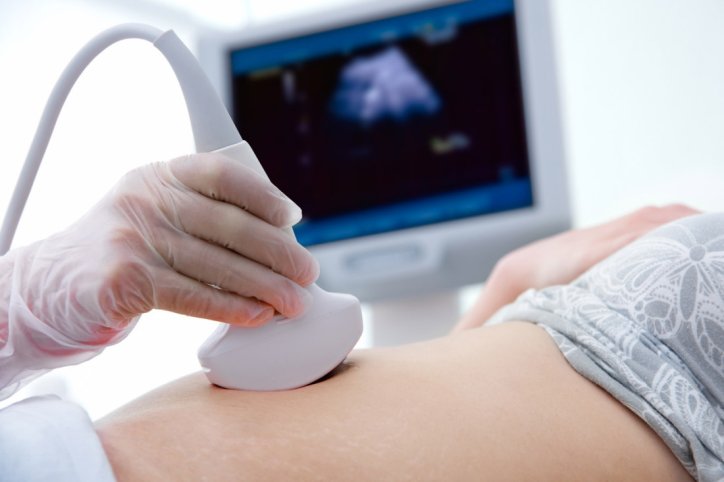Bei einer Schwangeren führt ein Arzt mithilfe eines Ultraschallgeräts eine Pränataldiagnostik durch.