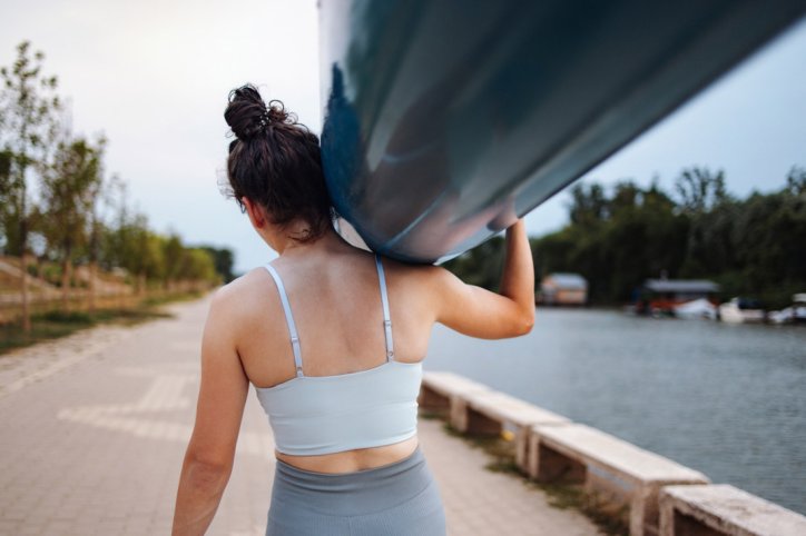 Eine Frau trägt ein Ruderboot