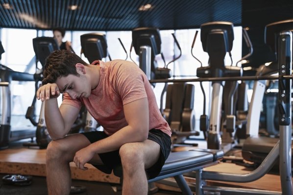 Ein Mann ist nach zu viel Training im Fitnessstudio erschöpft