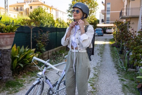 Eine etwa 25-jährige Frau schließt den Helm und will mit dem Fahrrad losfahren.