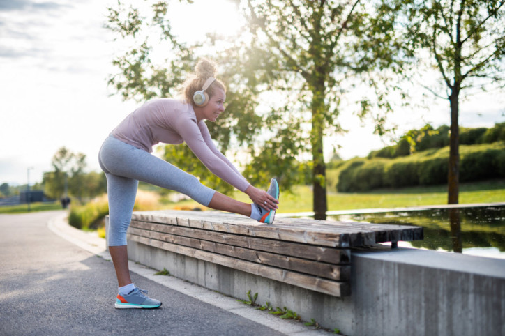 Eine Frau macht nach einem Training ein Cool Down an einer Parkbank