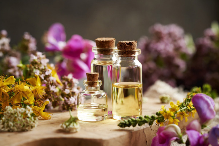 Verschiedene Flakons für eine Aromatherapie stehen zwischen Blüten