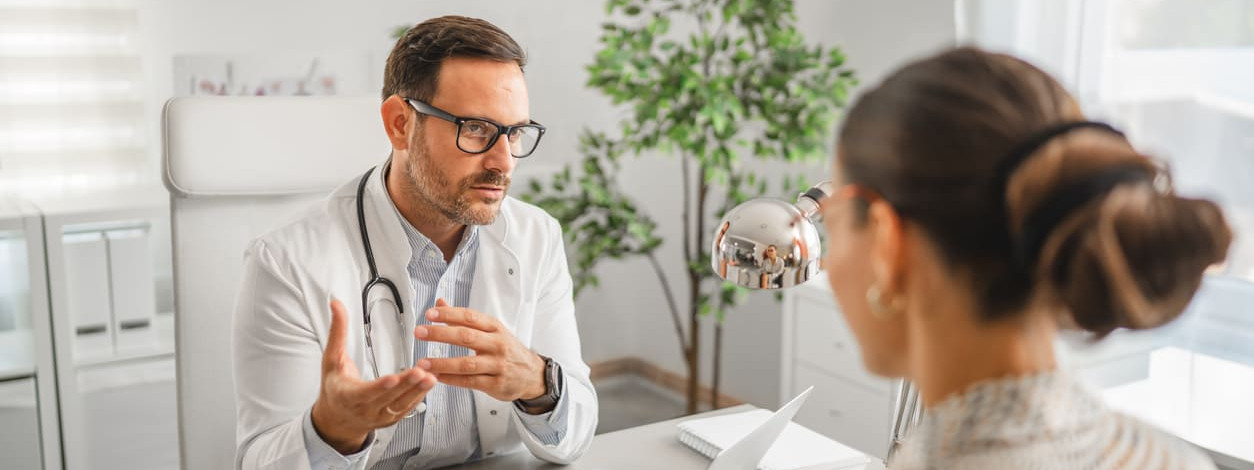 Ein Facharzt erklärt einer Patientin den Ablauf einer Biopsie