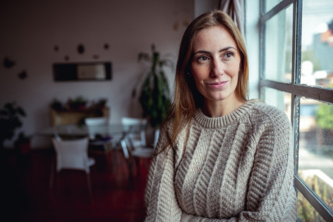 Eine circa 30-jährige Frau schaut schmunzelnd aus dem Fenster.
