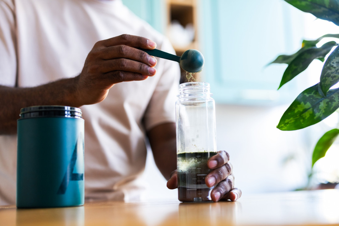 Eine Person mixt eine Shake Die Hände schütten ein Pulver in einen Shaker.