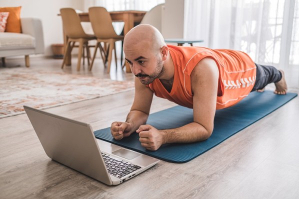 Mann mit Glatze macht Planking auf Sportmatte