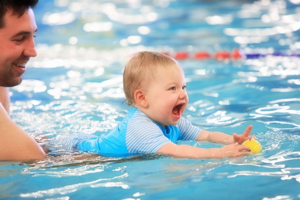 Vater und sein Baby beim Babyschwimmen im Pool.