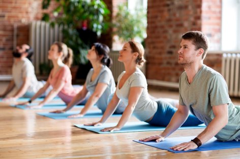Eine Gruppe nimmt an einem Präventionskurs teil. Sie machen Yoga auf der Matte.