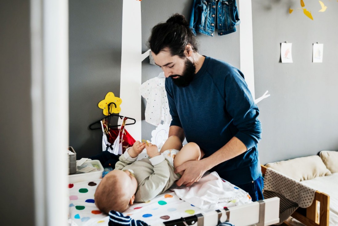 Ein Vater wickelt im Kinderzimmer sein Baby.