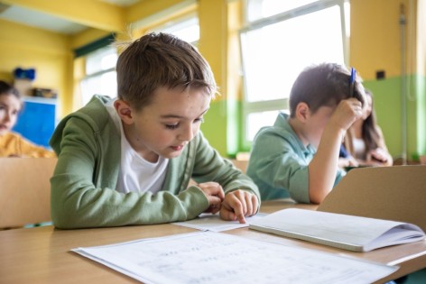 Ein etwa 9 jähriger Junge sitzt bei eine Logopädin und macht mit ihr gemeinsam Sprechübungen.