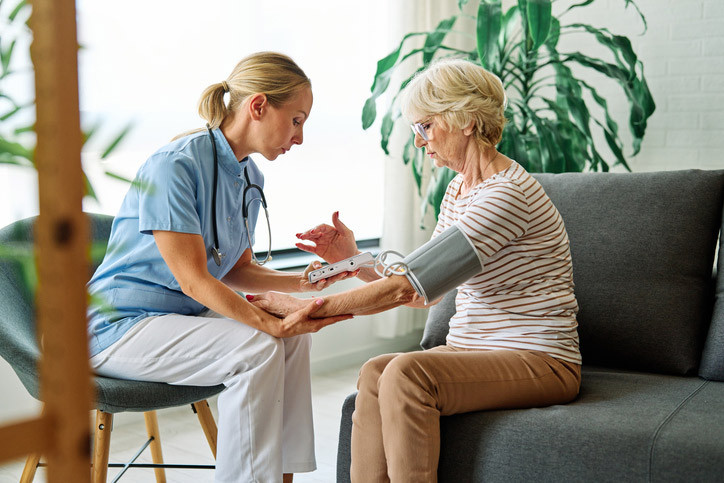 Eine Pflegefachkraft führt eine geriatrische Behandlung bei einer Seniorin durch