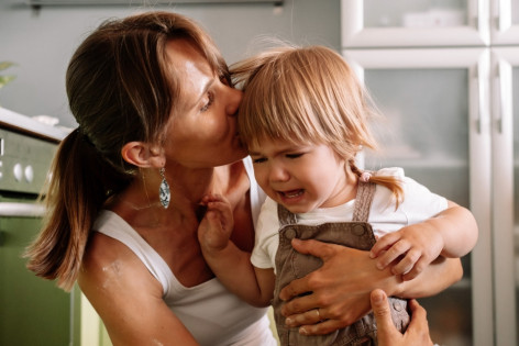 Eine Mutter tröstet ihr fremdelndes Kleinkind.
