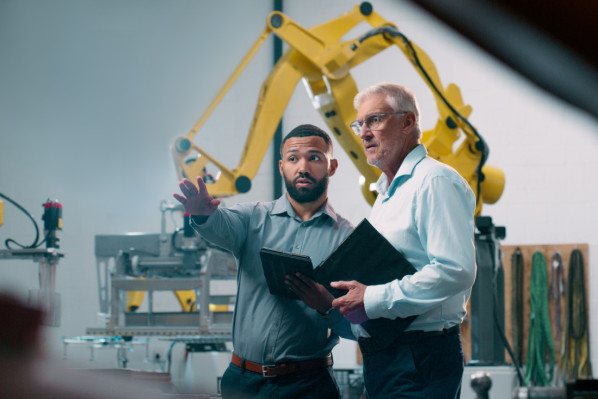 Robotics, people and engineer tablet with industrial collaboration and planning in warehouse. Factory, engineering and futuristic work of manufacturing management with discussion for cnc automation