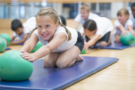 Mädchen führt sportliche Übung mit Ball durch
